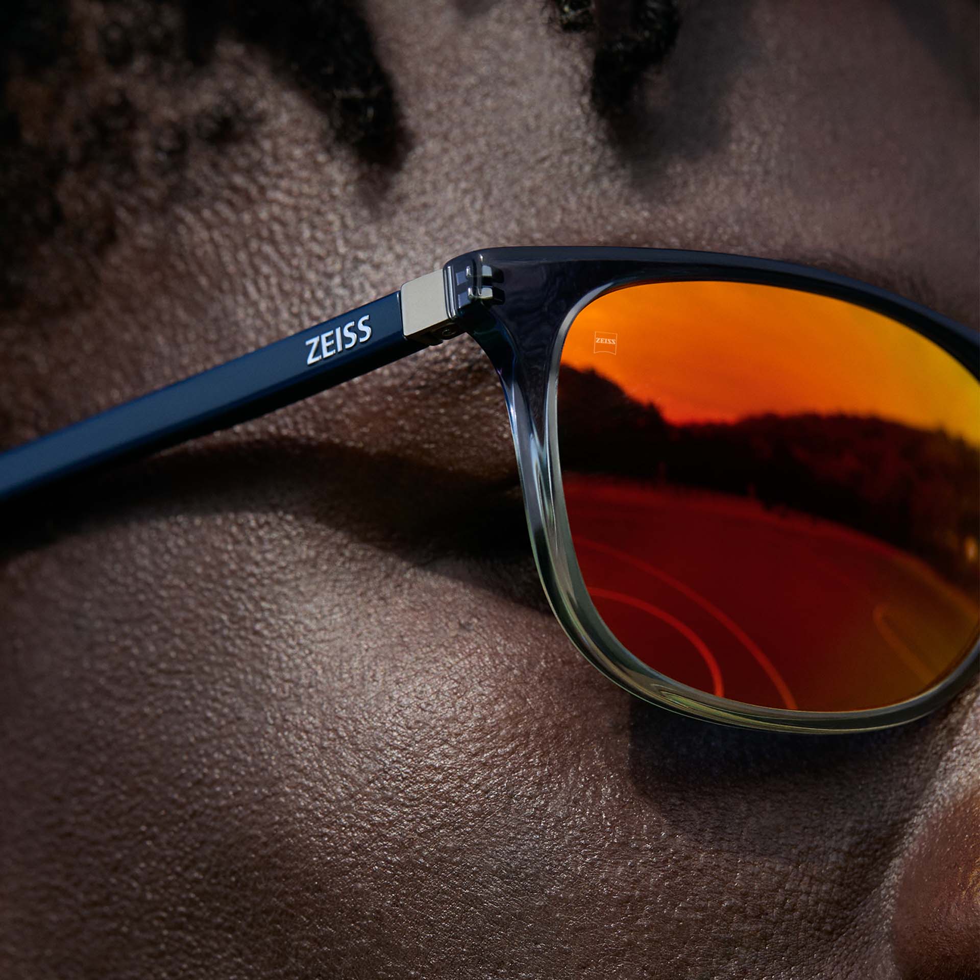 Close-up of a man wearing ZEISS Eyewear with ZEISS DuraVision Mirror UV sunglass coating in orange colour.