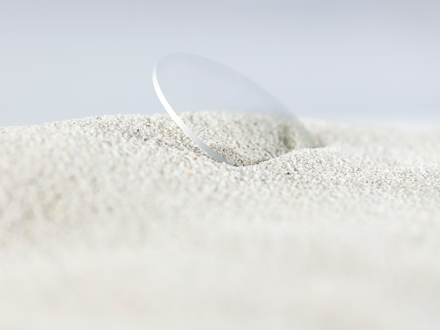 A ZEISS lens with a durable coating is covered in rough sand but still scratch-free.